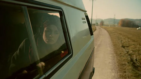 protagonist in VW bus, looking out of the window