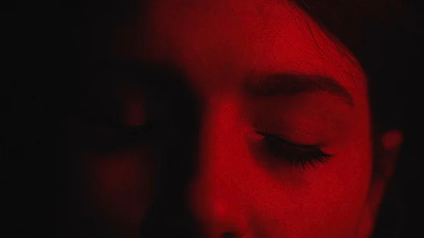 Stephi Venier, in a dark room, with Atomic red reflecting from her face