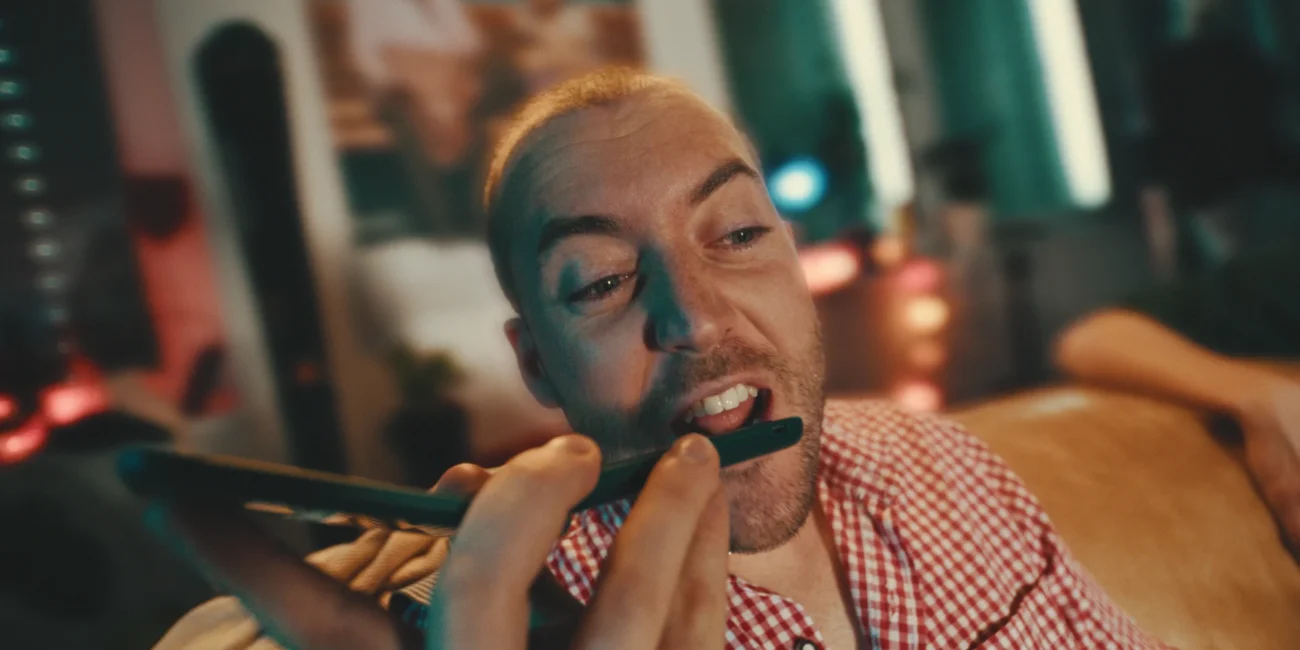 Close-up of comedian Austrian Kiwi performing as 'Hannes' during the high-stakes phone call scene, showcasing expressive character acting.