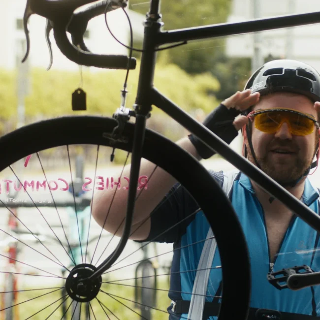 Dramatic cinematic character portrait from the Holy Moly Films production, featuring a character in a bike helmet and safety glasses.