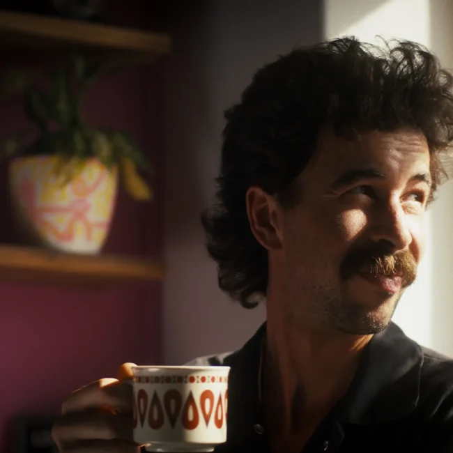 A high production value cinematic still from the Holy Moly Films comedy short film, capturing a character holding a coffee cup, beautifully lit.