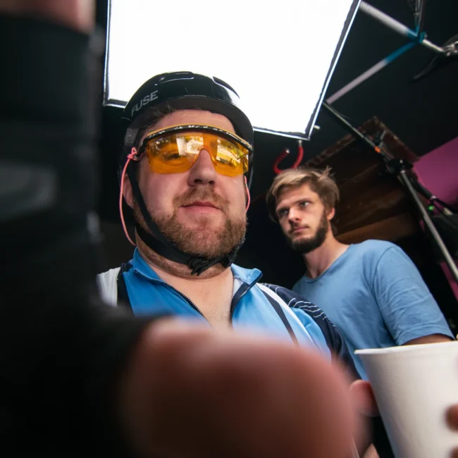 A creative extreme low-angle behind-the-scenes shot of Holy Moly Films directing a comedic actor on set in Salzburg.