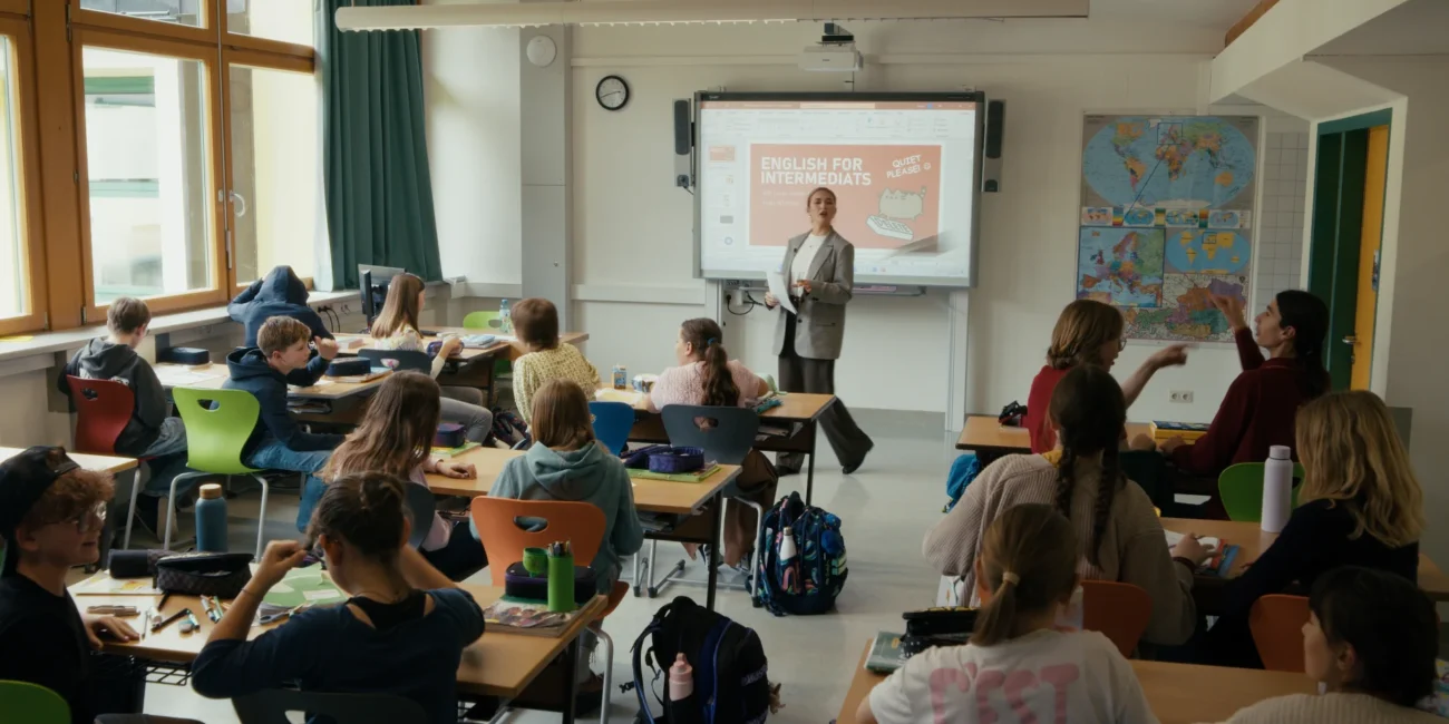 Wide shot of a bright Austrian secondary school classroom at HIB Saalfelden during the filming of a comedy sketch by Holy Moly Films.