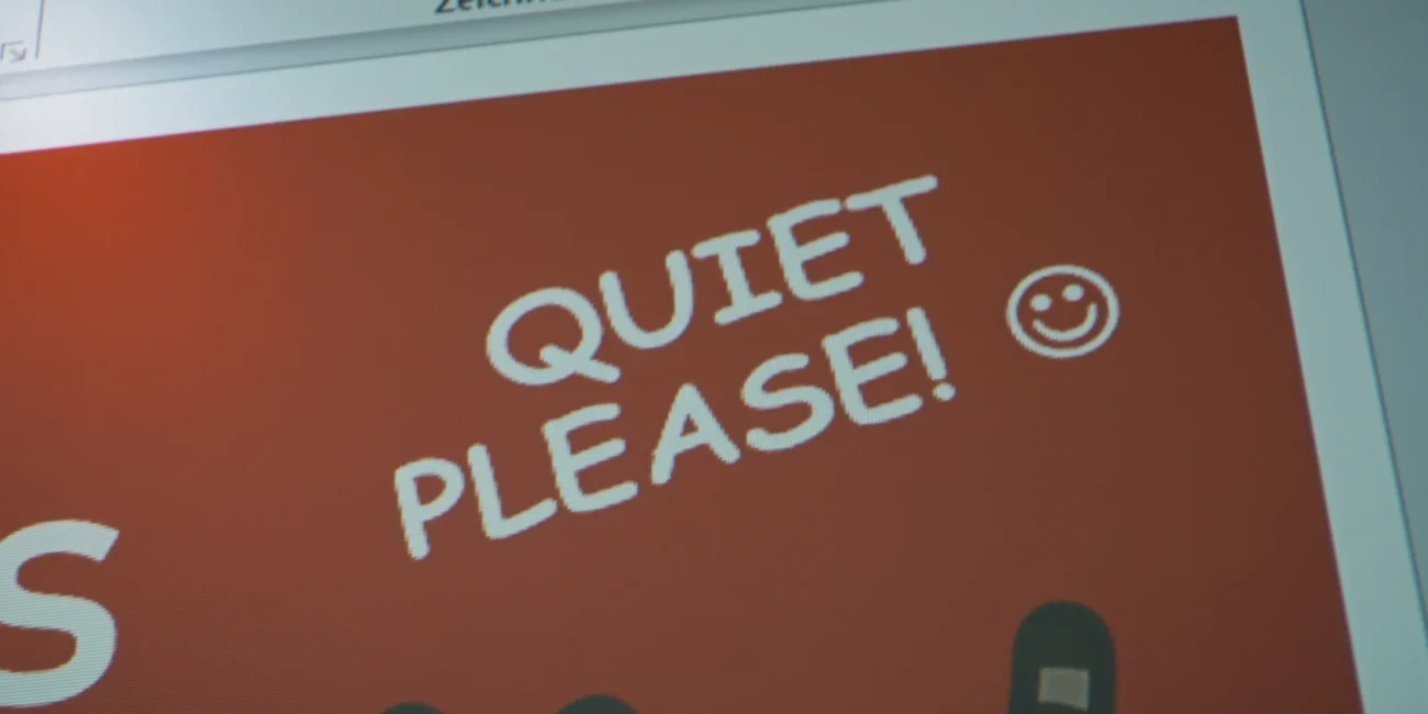 Presentation slide projected on the classroom screen displaying the phrase "Quiet please" during the video short.