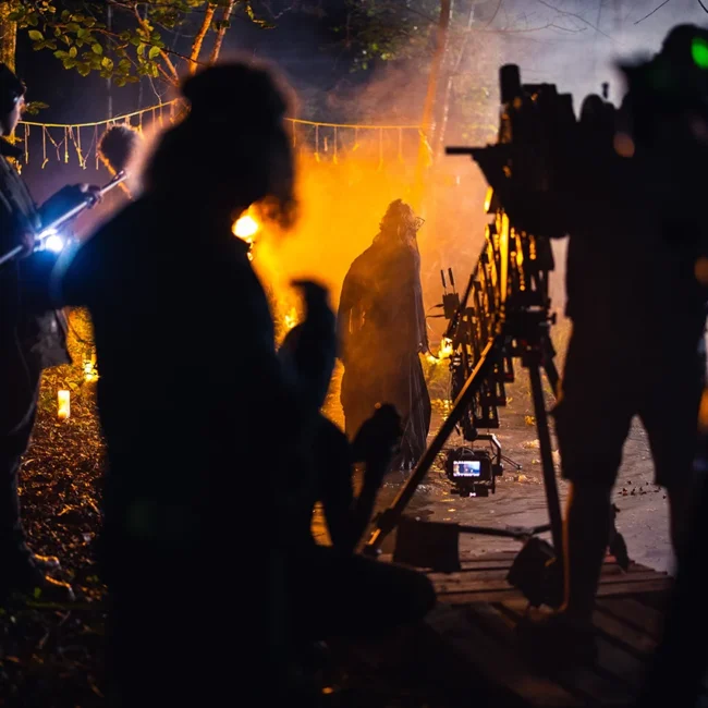 Behind-the-scenes night shot of Holy Moly Films crew operating camera and sound equipment on a atmospheric dark fantasy short film set in the woods.
