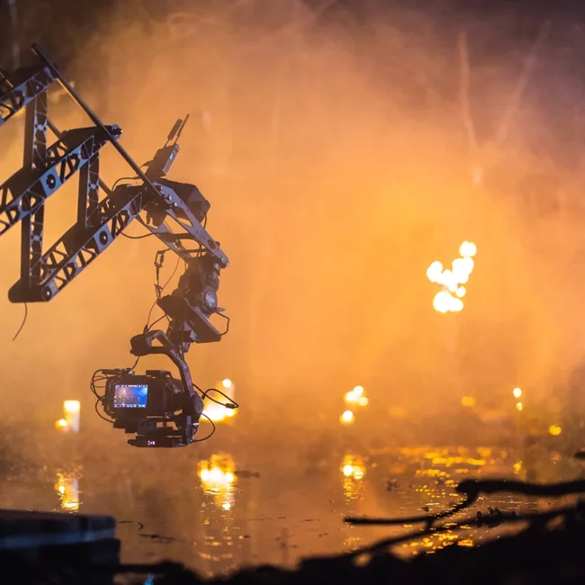 High-end cinema camera mounted on a jib crane and gimbal over water with fiery lighting effects during the filming of HECATE.