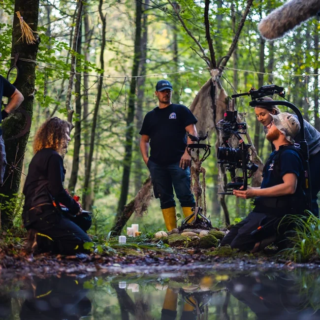 Film crew preparing a scenic forest shot with a ritual altar setup for a high-end narrative short film production.