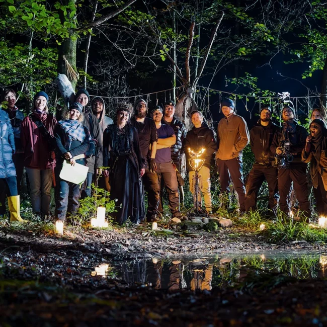 Full cast and crew of Holy Moly Films posing together at night on the forest set of the dark fantasy short film HECATE.