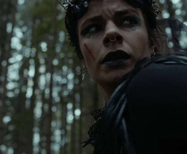 Close-up film still of Selina Pöstinger playing the witch with dark makeup and a twig crown in HECATE.