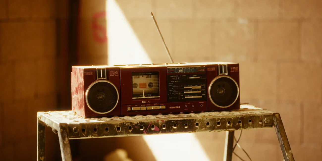Retro red boombox radio resting on a metal stepladder on a warm-toned construction site film set from Holy Moly films.