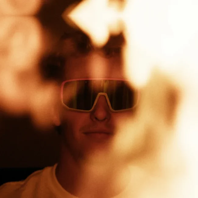 Portrait of a craftsman wearing the Perwein x Naked Optics glasses surrounded by fire.